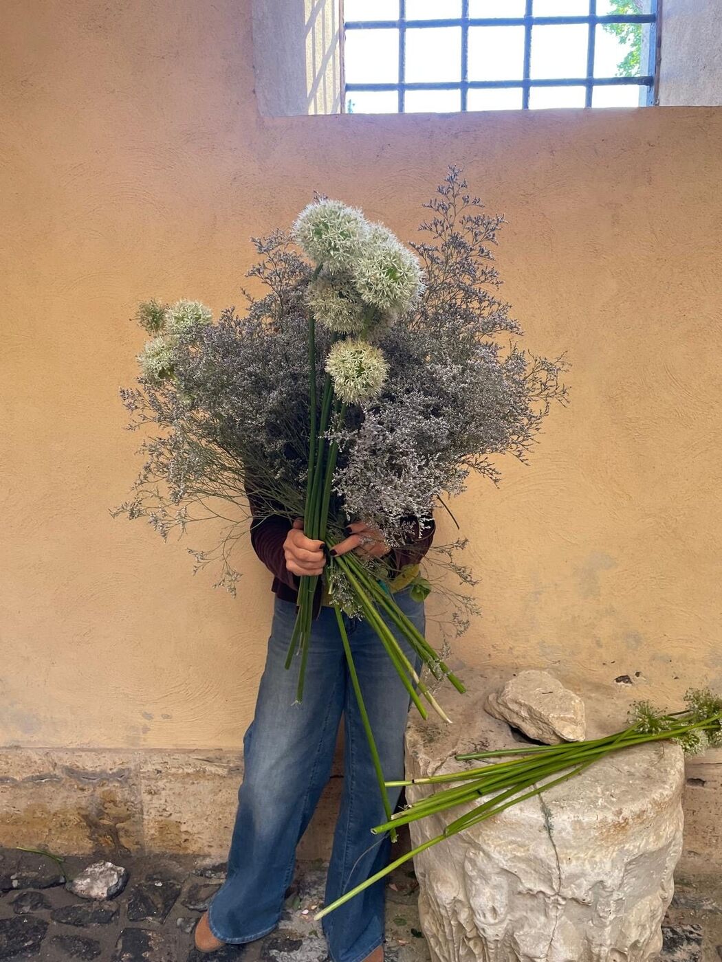 Un grande mazzo di fiori e rami secchi tenuto tra le braccia