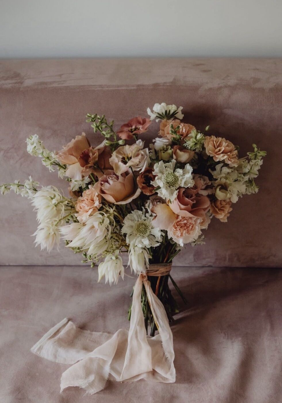 Bouquet nei toni pesca e crema legato con un nastro di seta