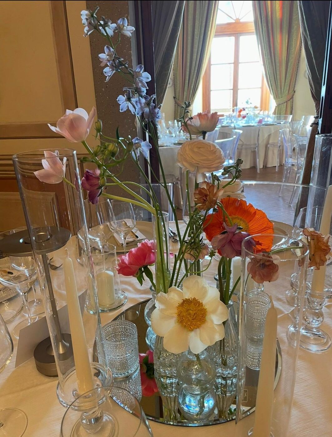 Centrotavola di ranuncoli, papaveri e peonie in vasetti di vetro su una tavola apparecchiata